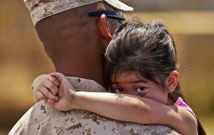 Photo of military person hugging girl